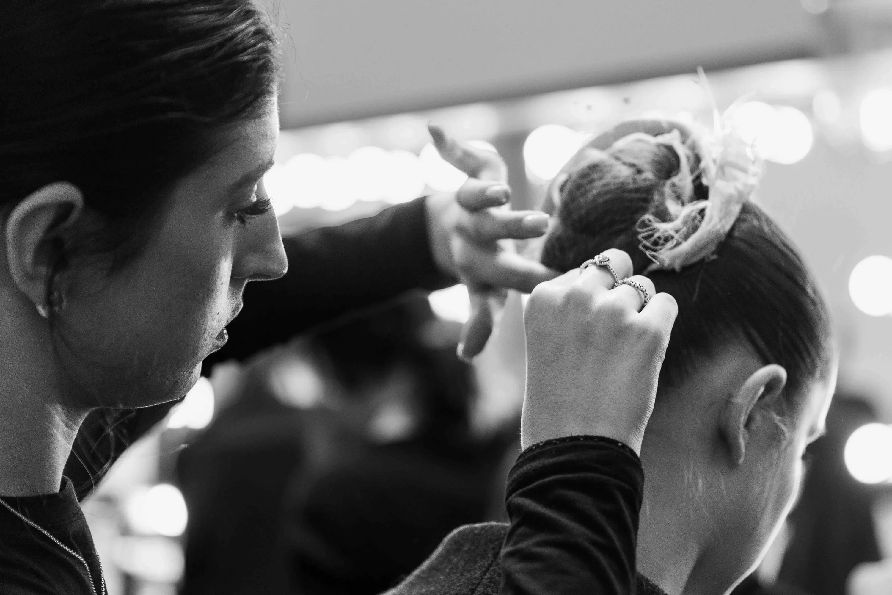 A ballerina has her hair done before the mirror