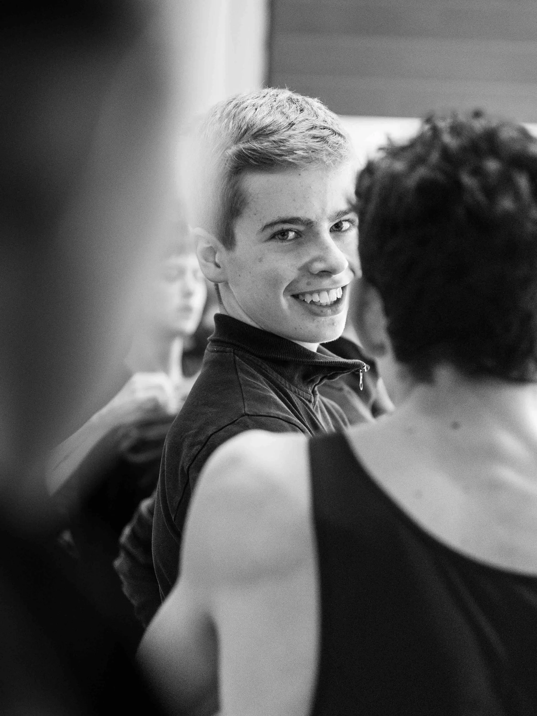 A dancer smiles as he turns among his colleagues