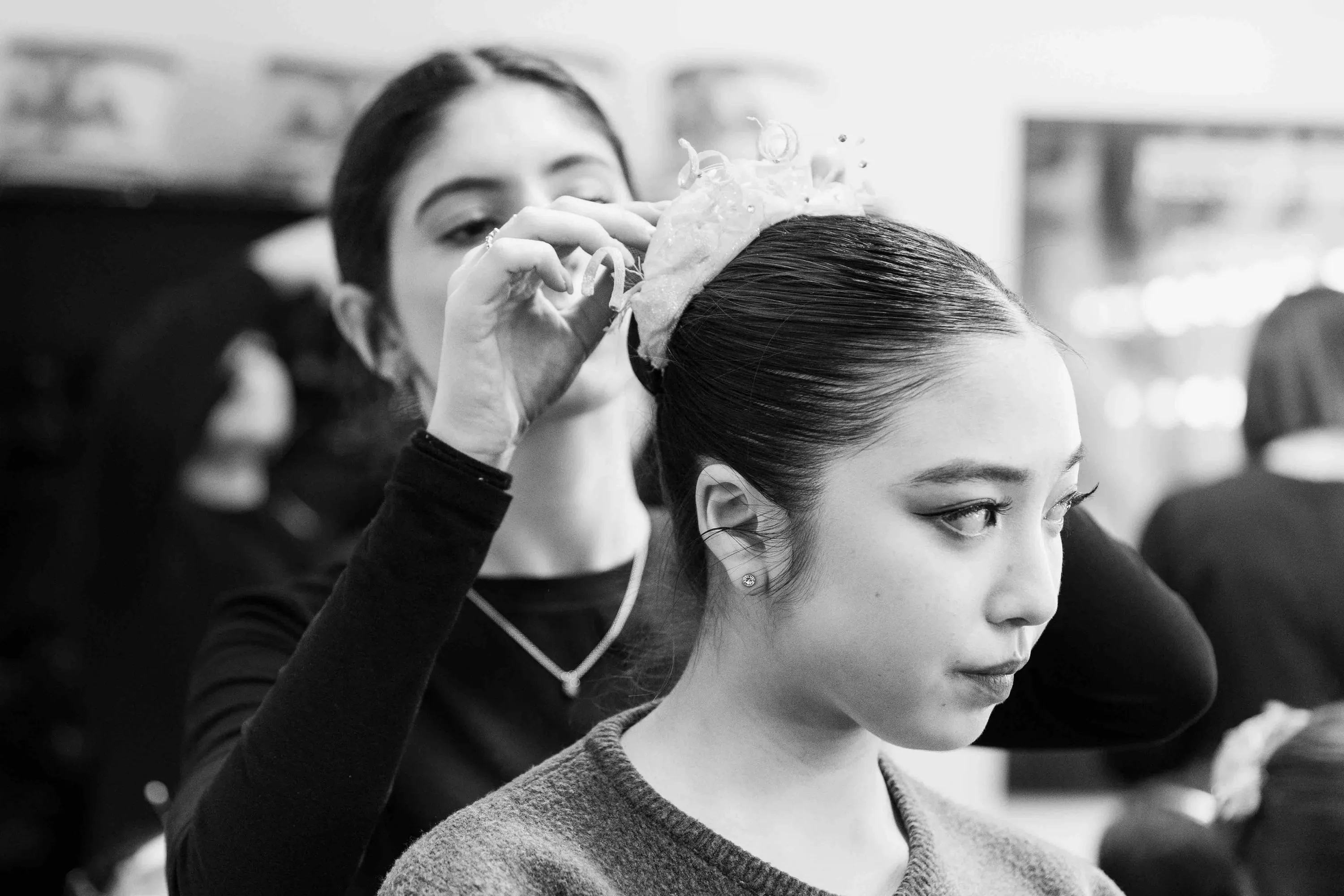 A woman fixes a hair ornament on a ballerina