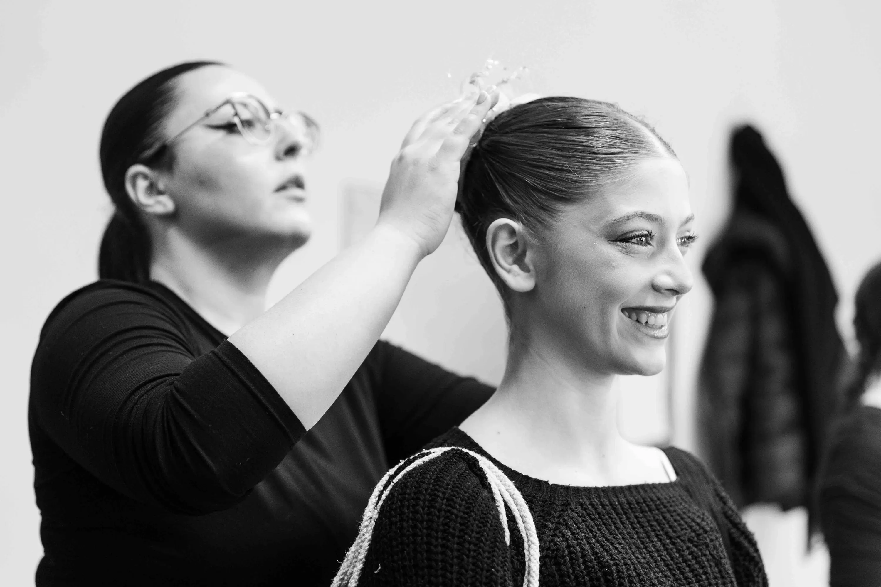A ballerina smiles as her hair is arranged