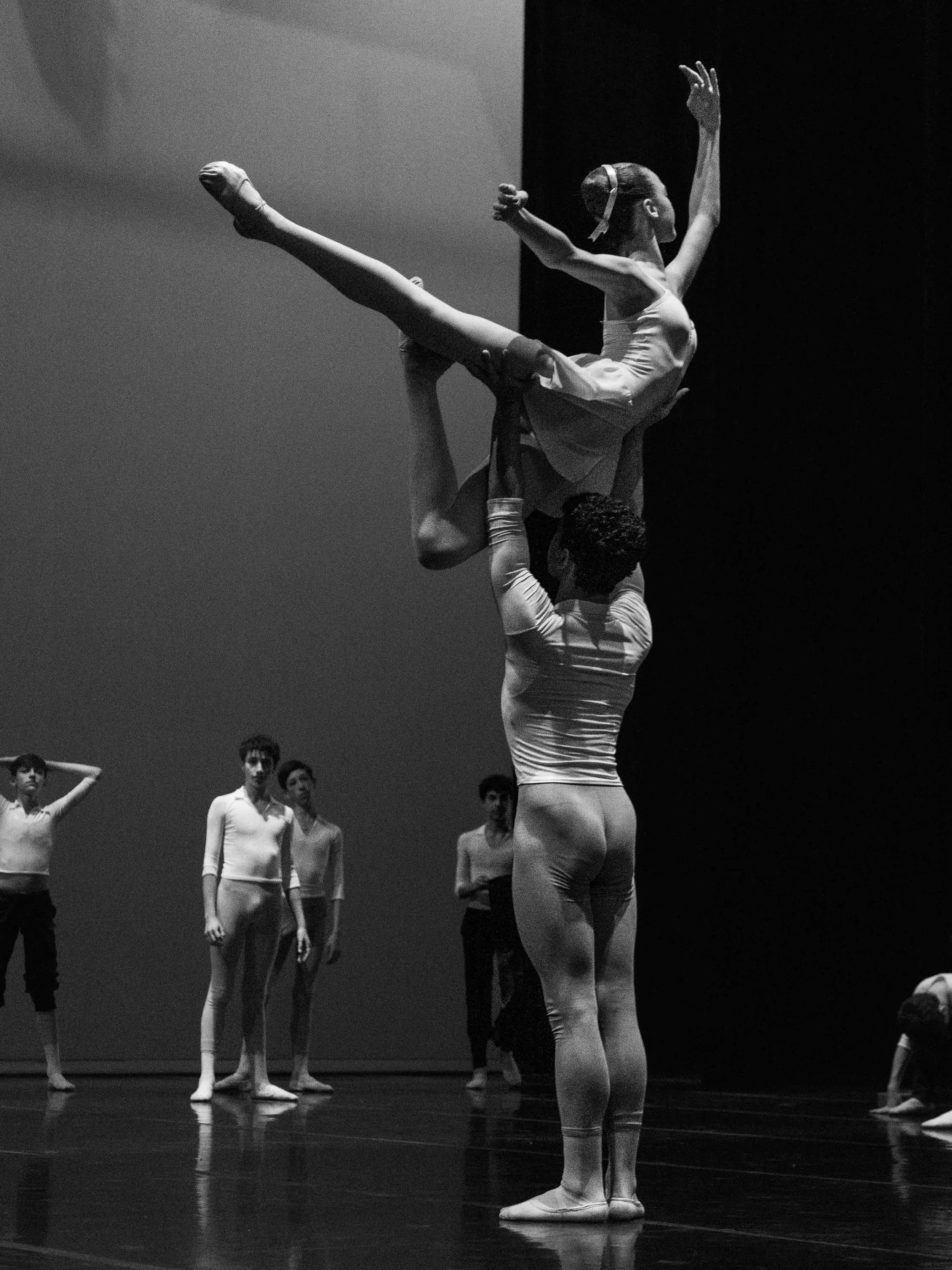 A ballerina lifted high by her partner during rehearsal