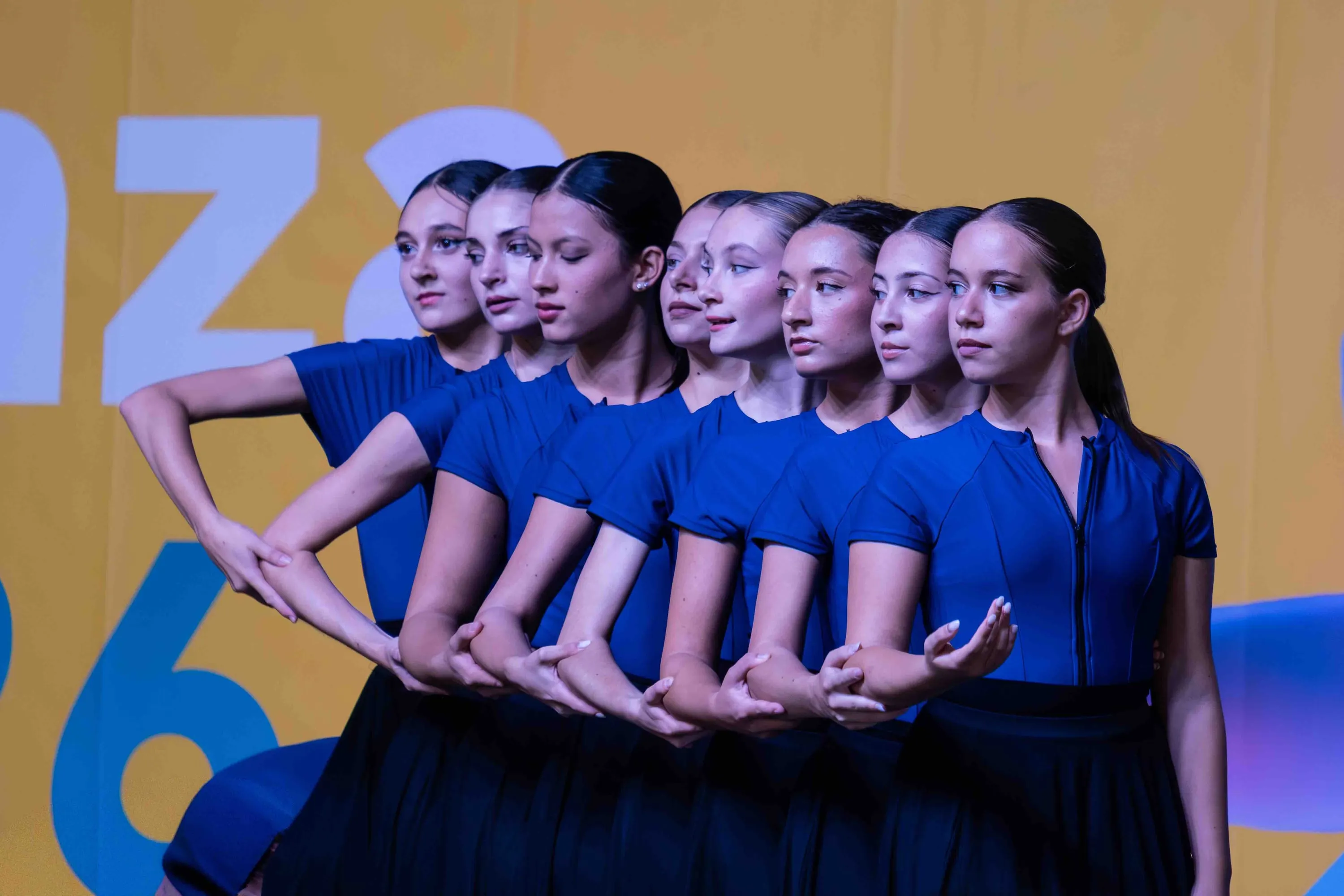 A row of dancers in blue, their faces aligned in profile