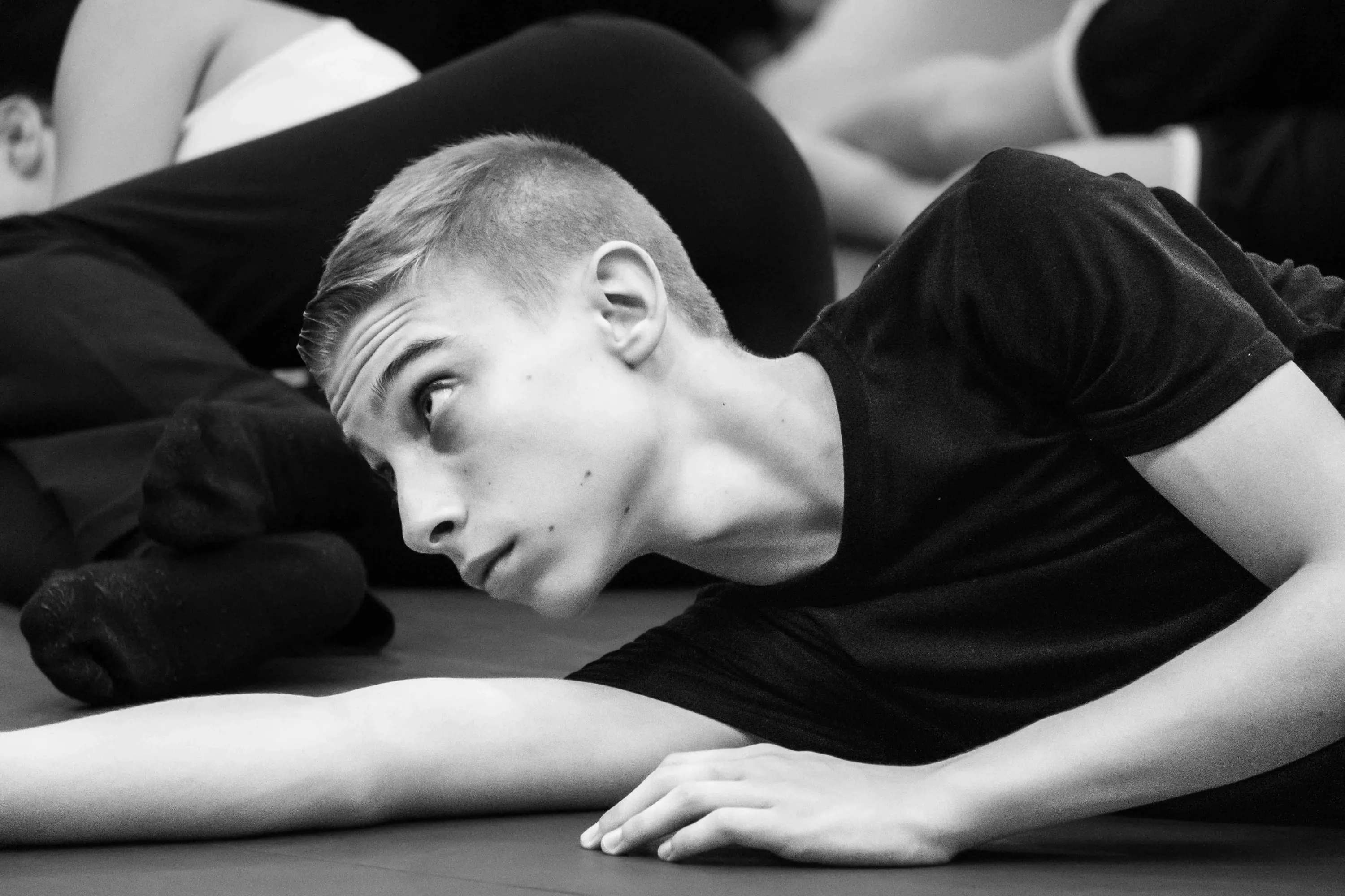A young student lying on the floor looks upward