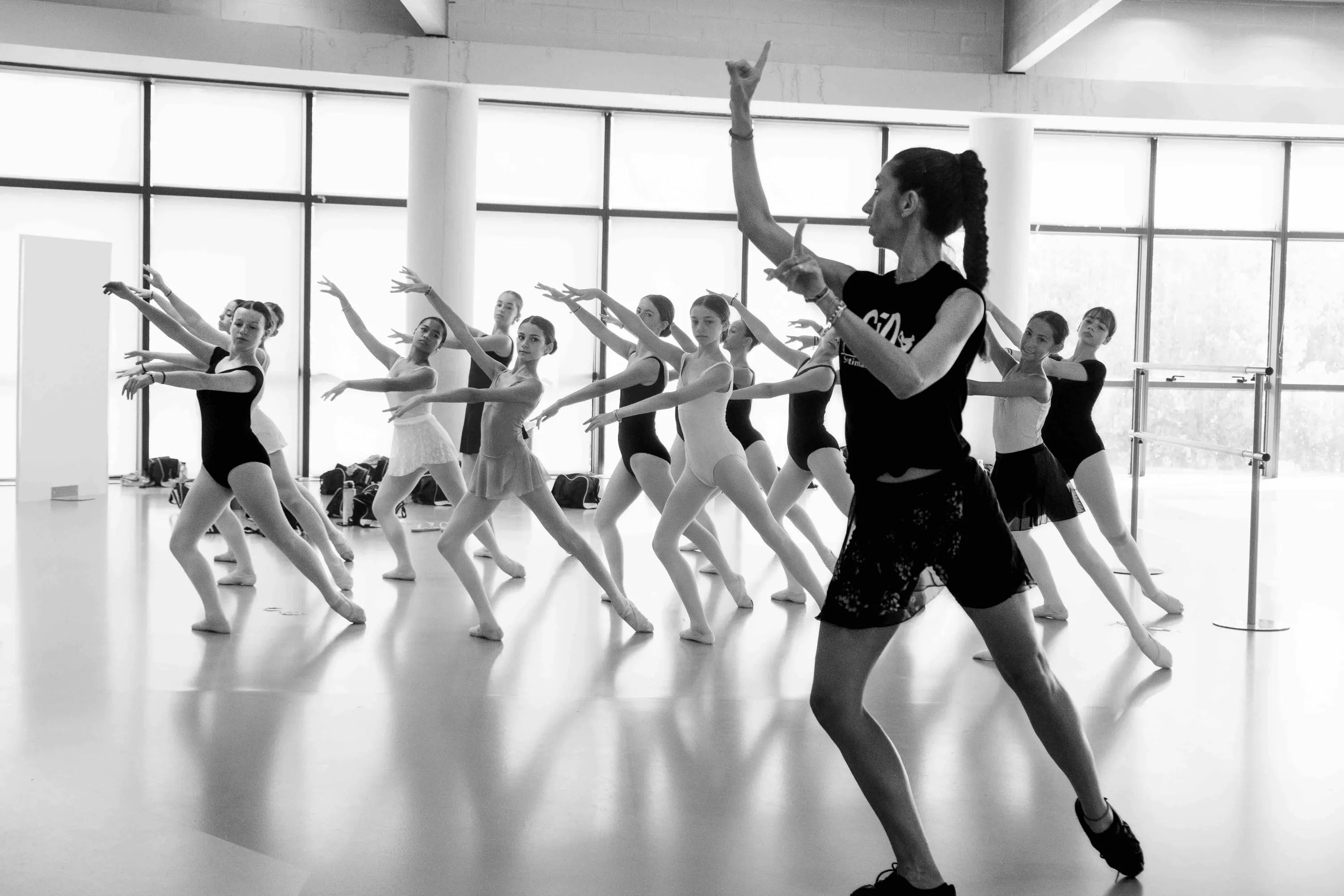The teacher leads a group of students in a large bright studio