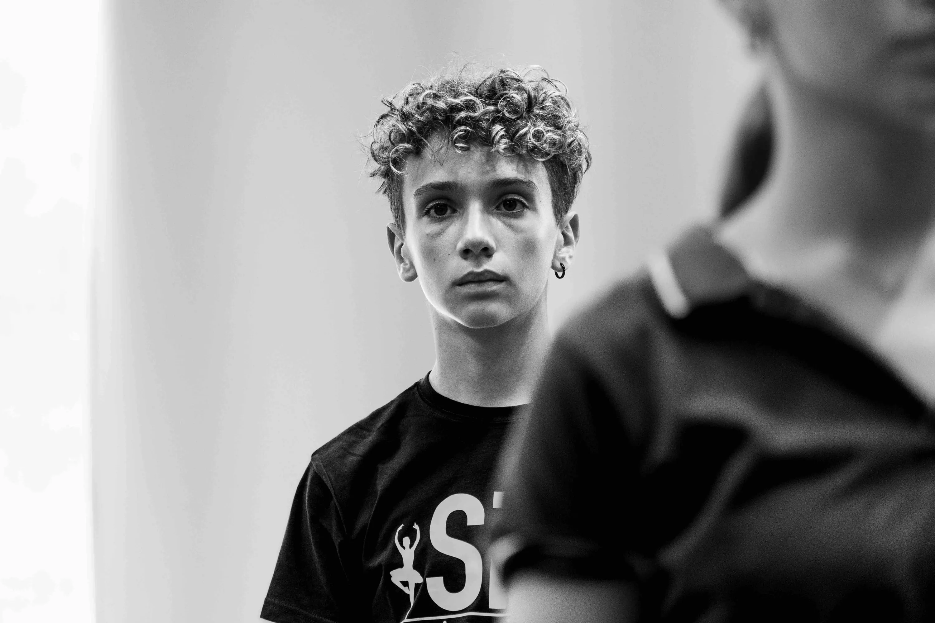 A young curly-haired student looks into the camera