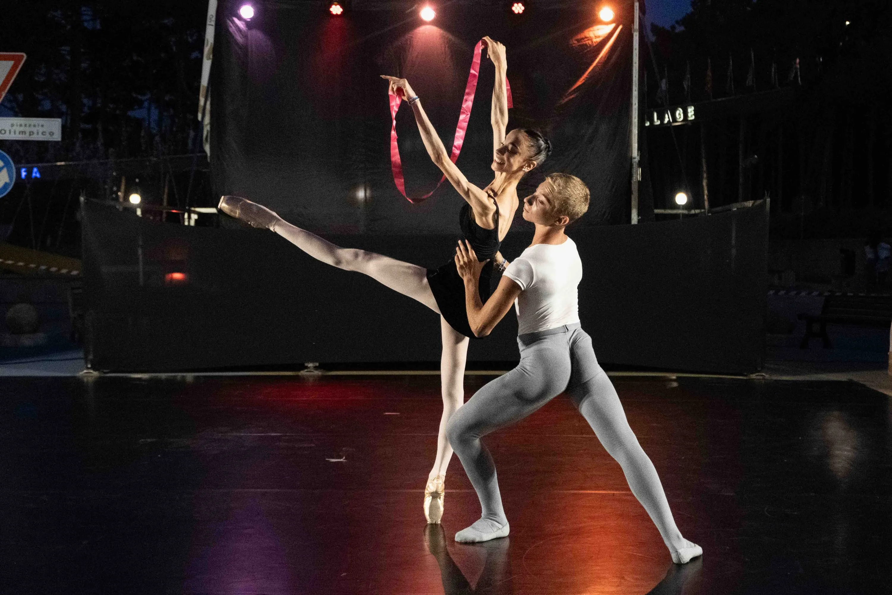 Two dancers with ribbons on an outdoor stage at night