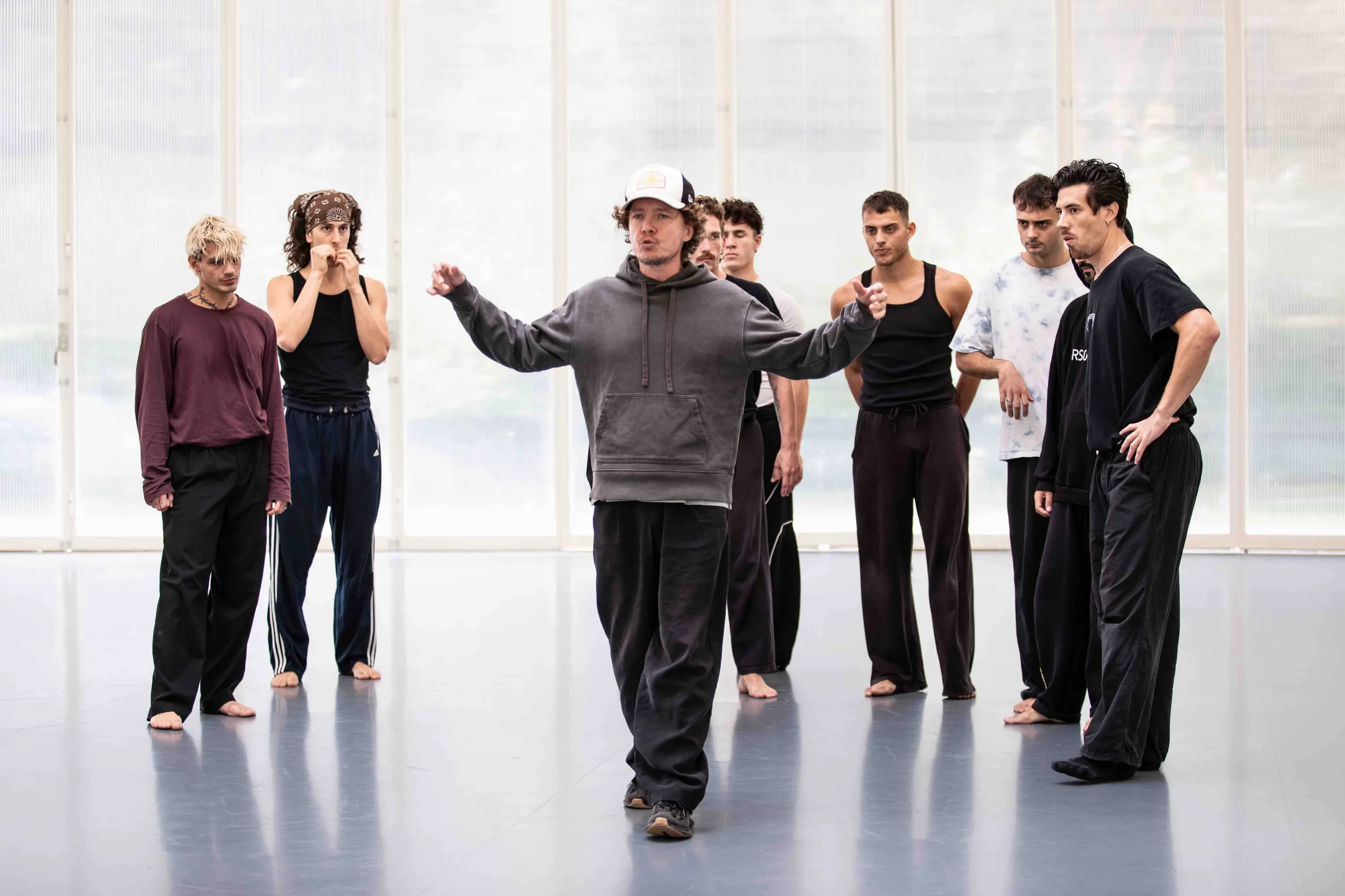 Dancers listen to the choreographer in a bright studio