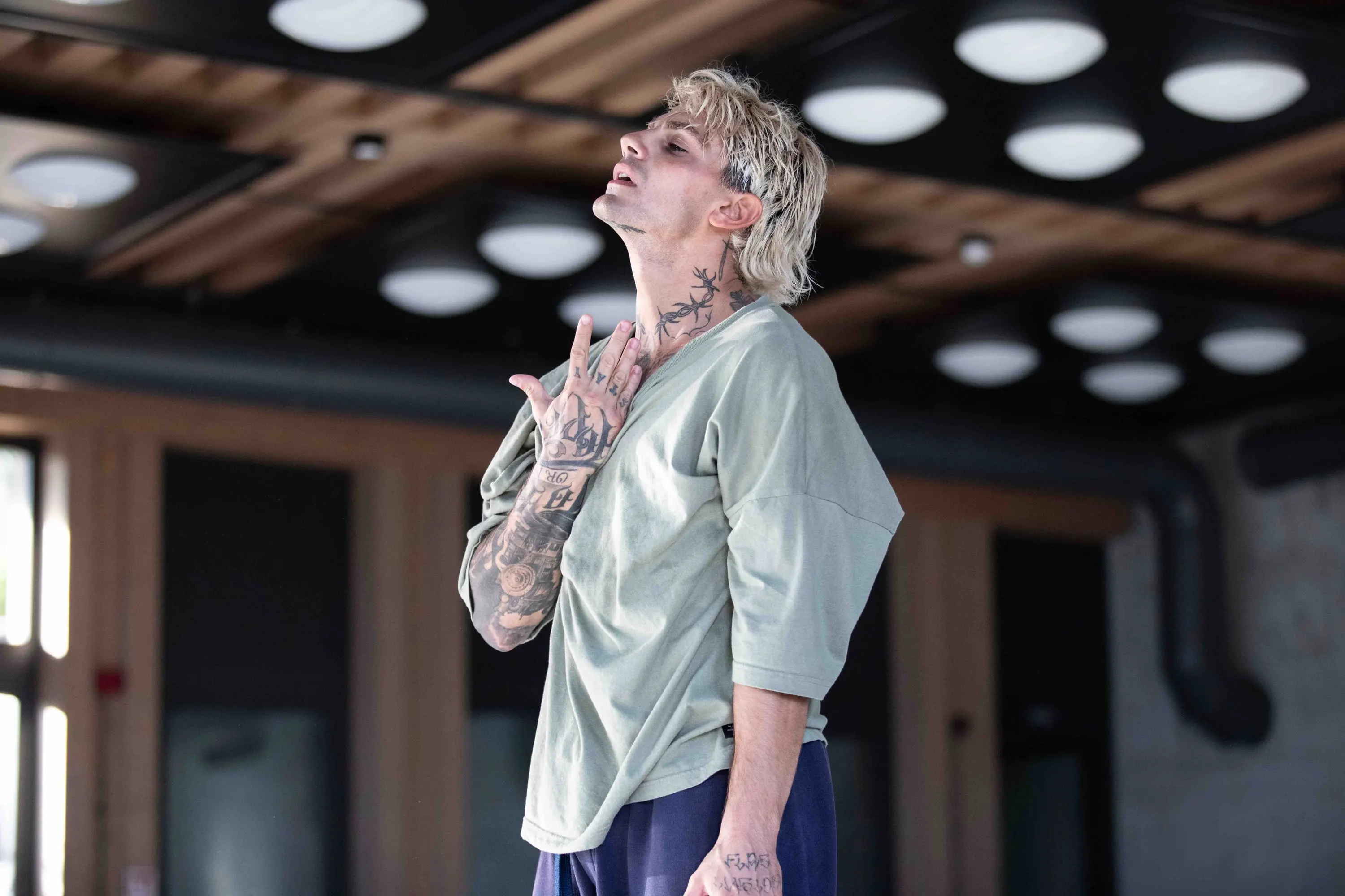 A tattooed dancer looks upward in the rehearsal studio