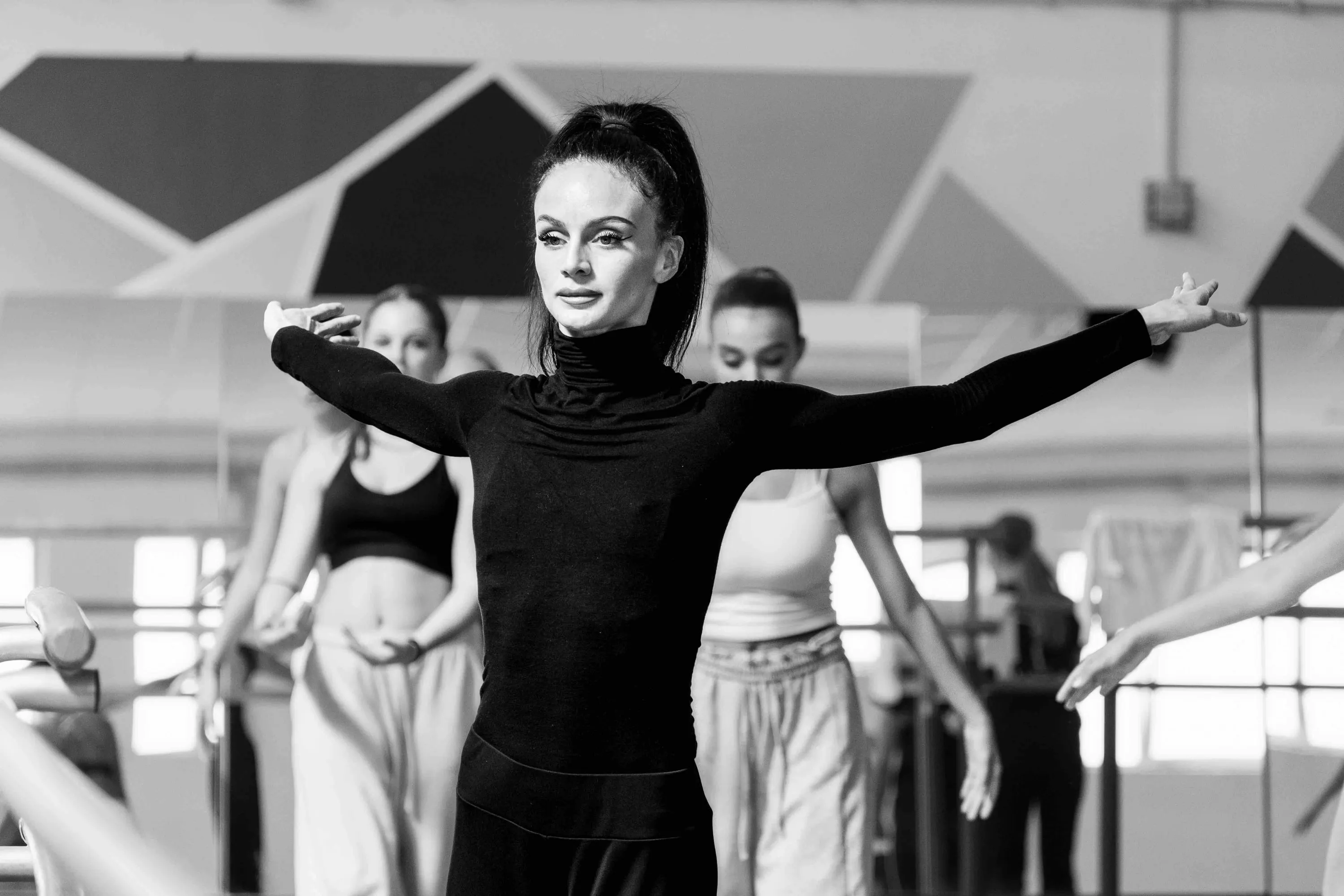 The teacher in black with arms open before the students