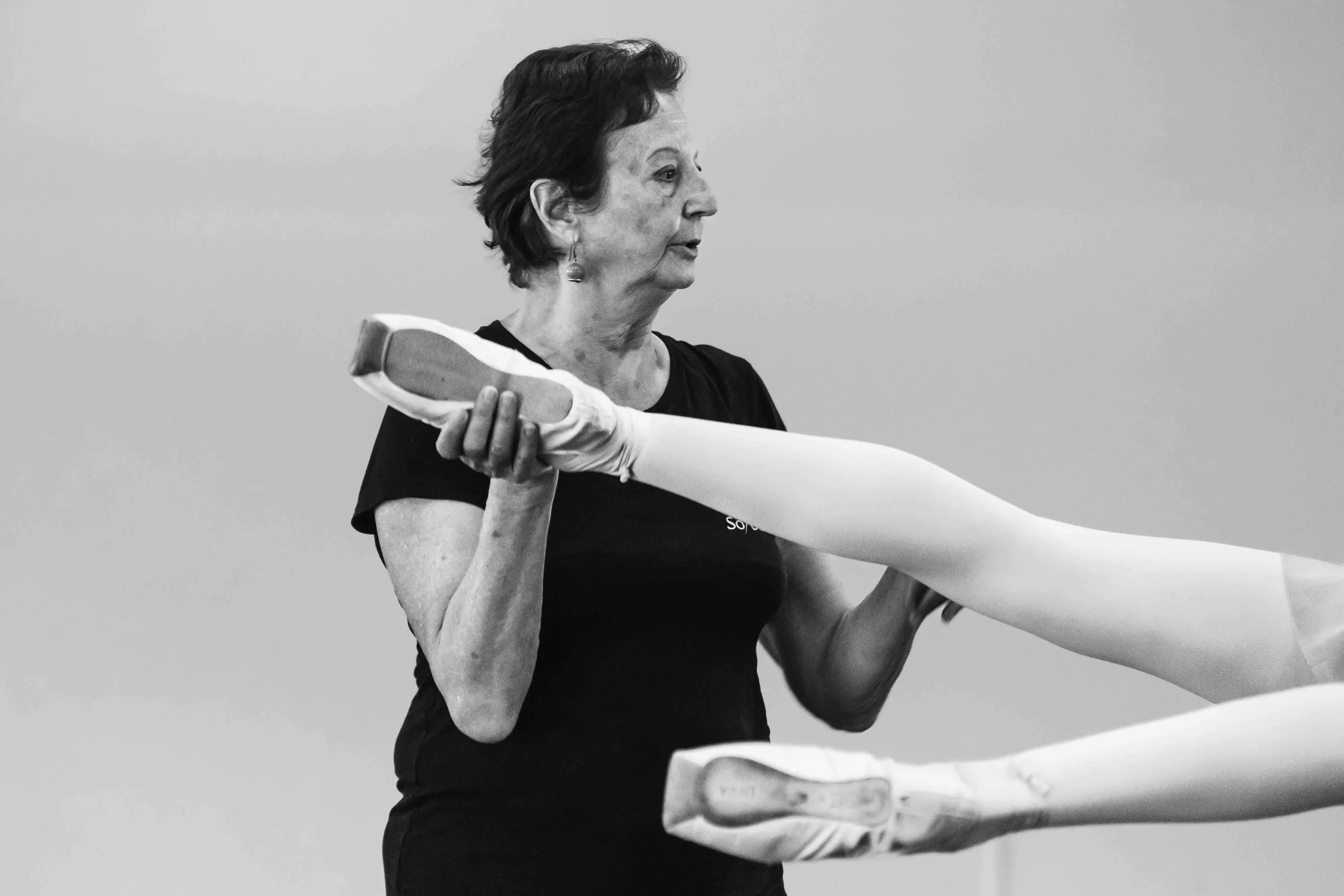 The teacher holds a student's pointed foot