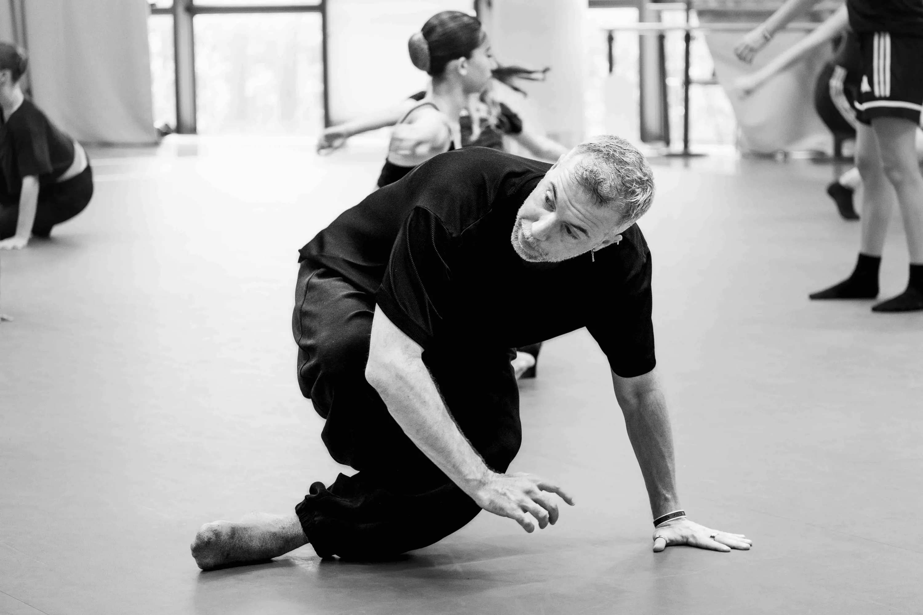 The teacher, low to the floor, demonstrates a sequence