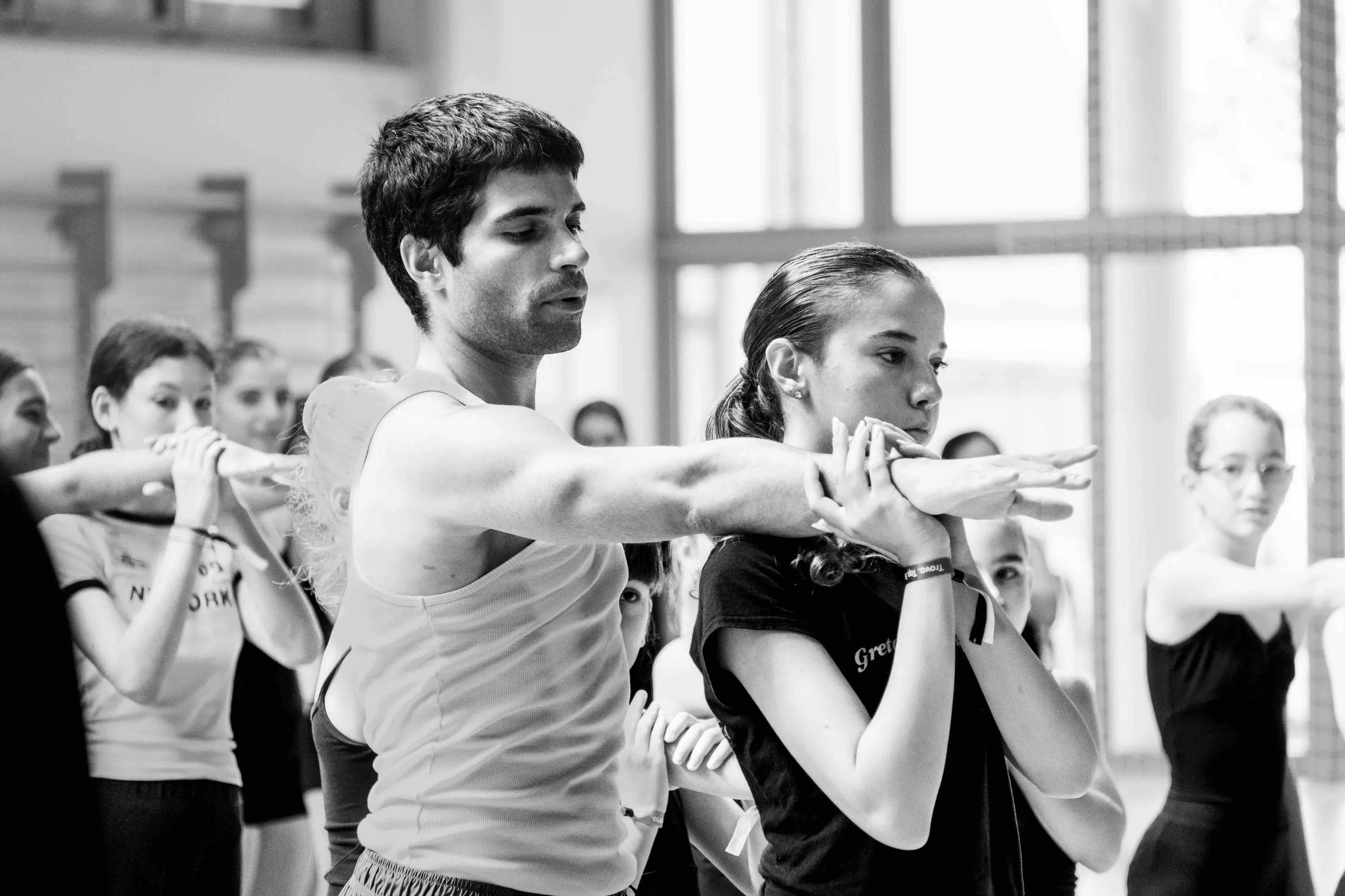The teacher demonstrates an arm movement alongside a student