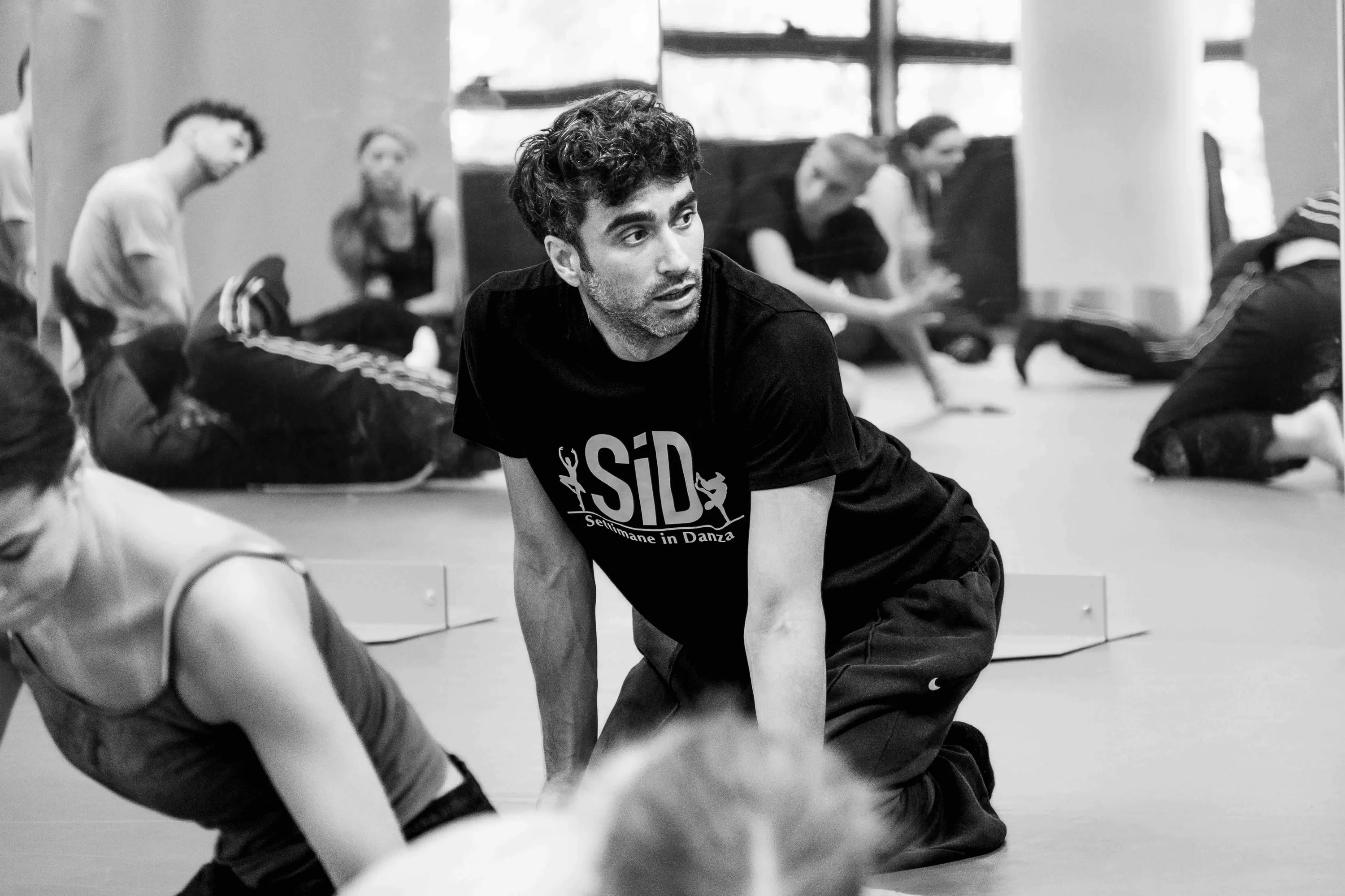 The teacher crouching among students on the floor