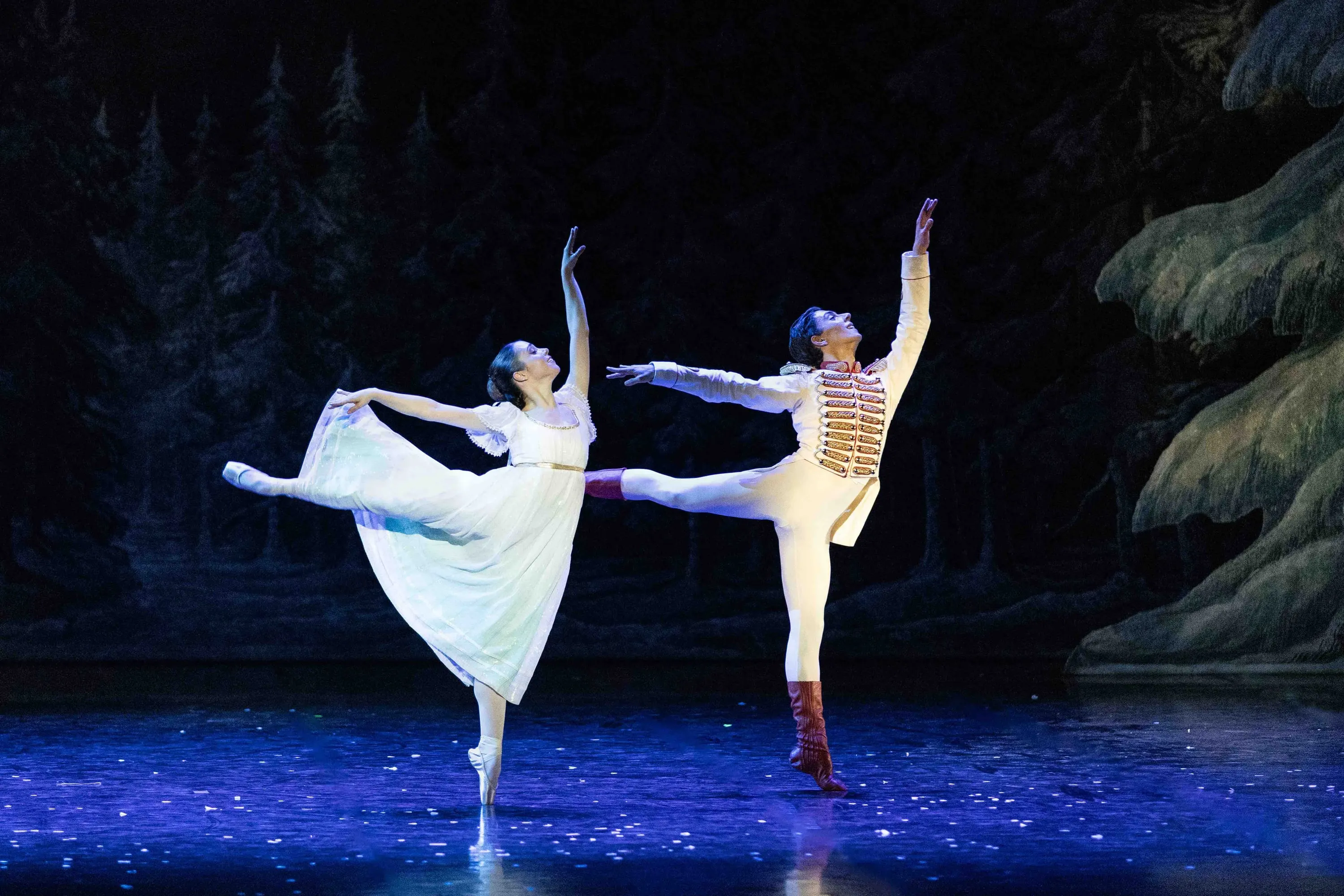 Two dancers in arabesque in the snowy forest, blue light