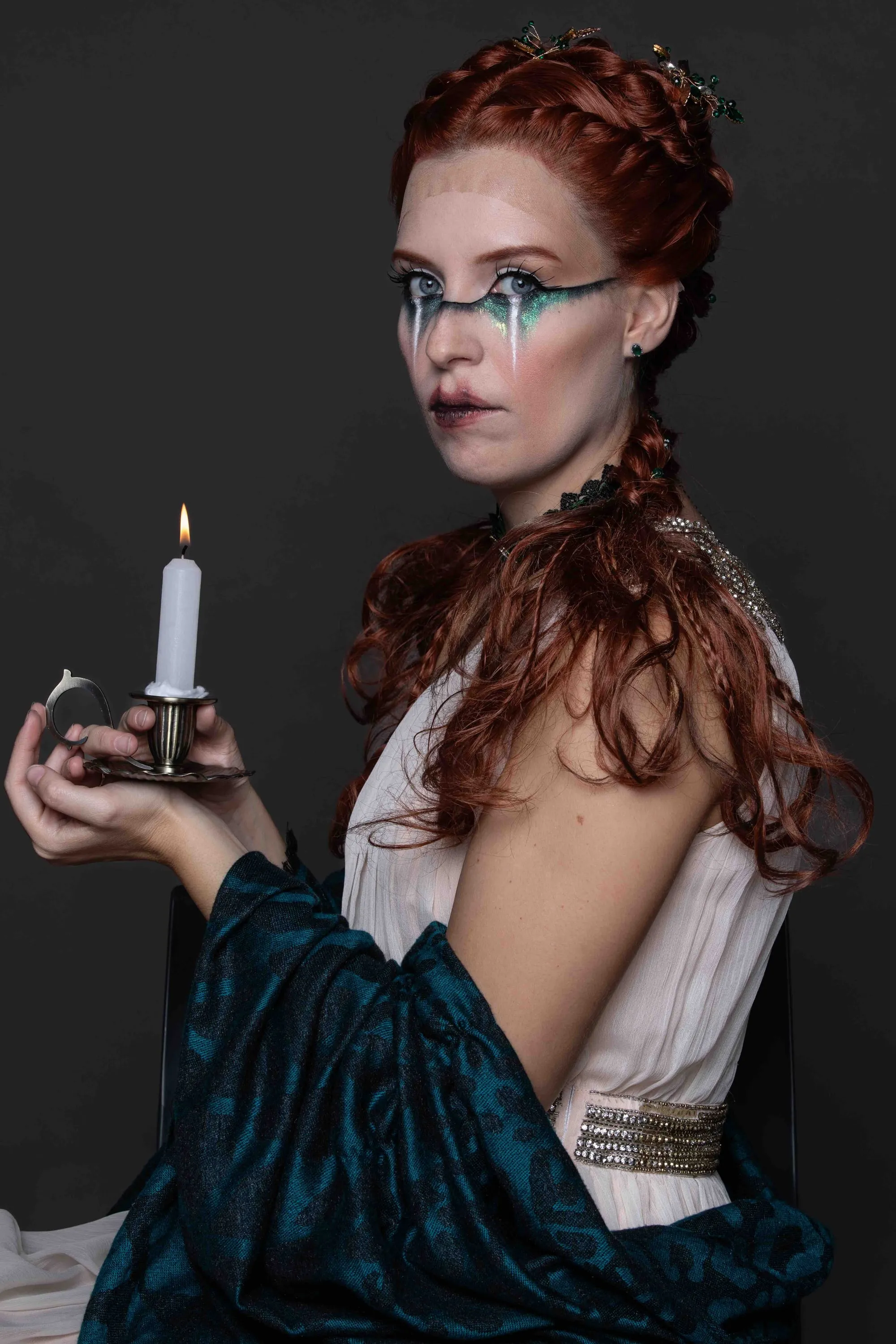 A red-haired model with painted blue tears and a candle
