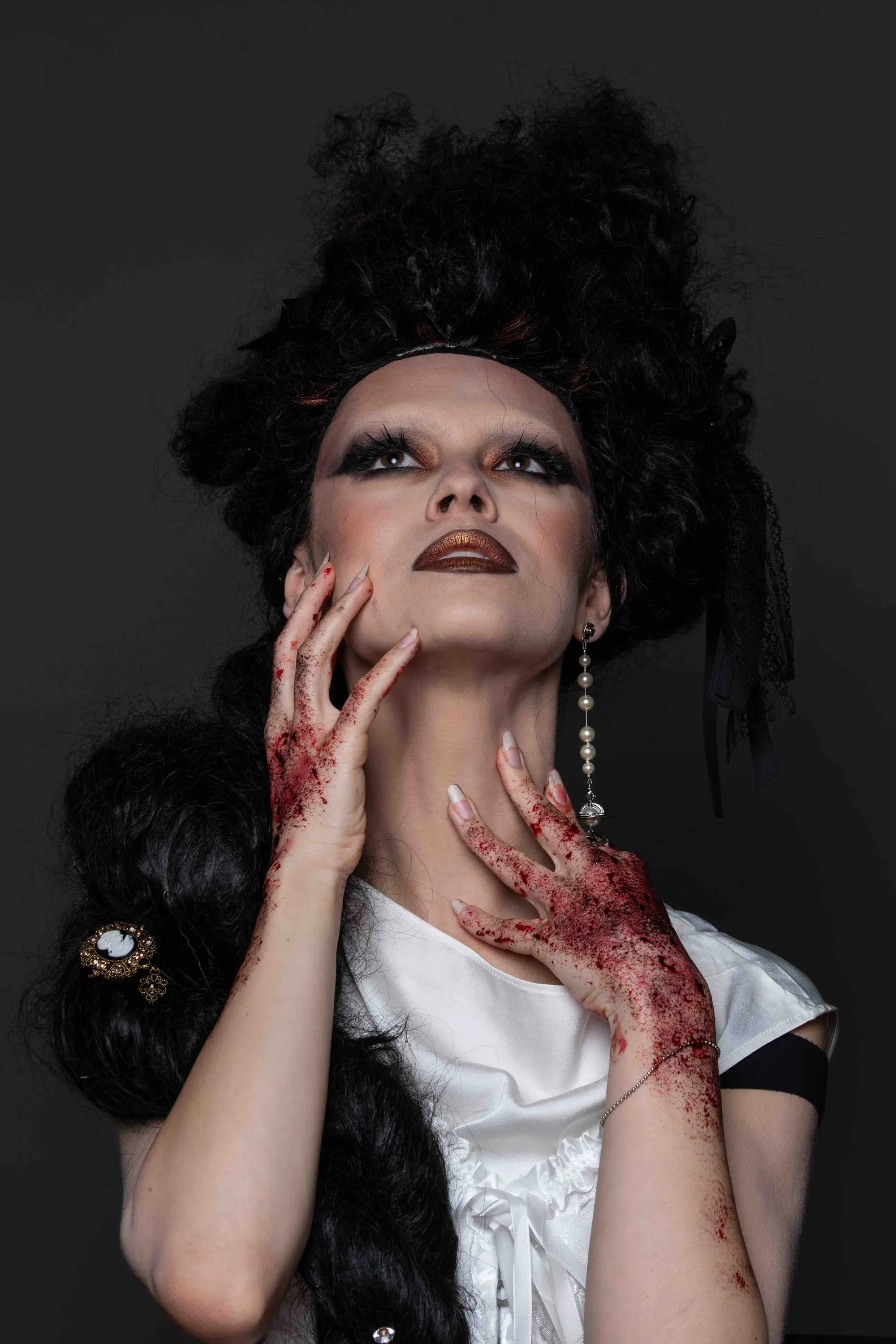 Theatrical make-up with bloodied hands and a tall hairstyle