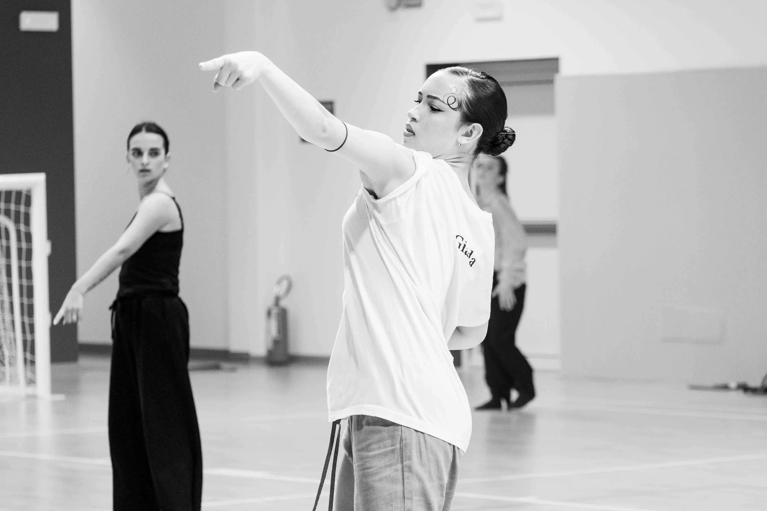A teacher demonstrates a port de bras to students in a gym