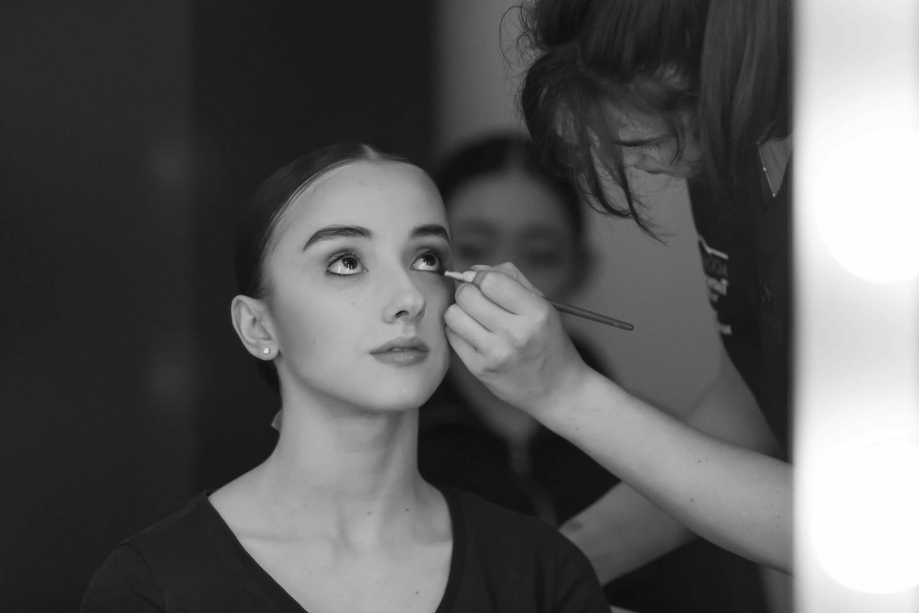 A ballerina being made up, eyes turned upward