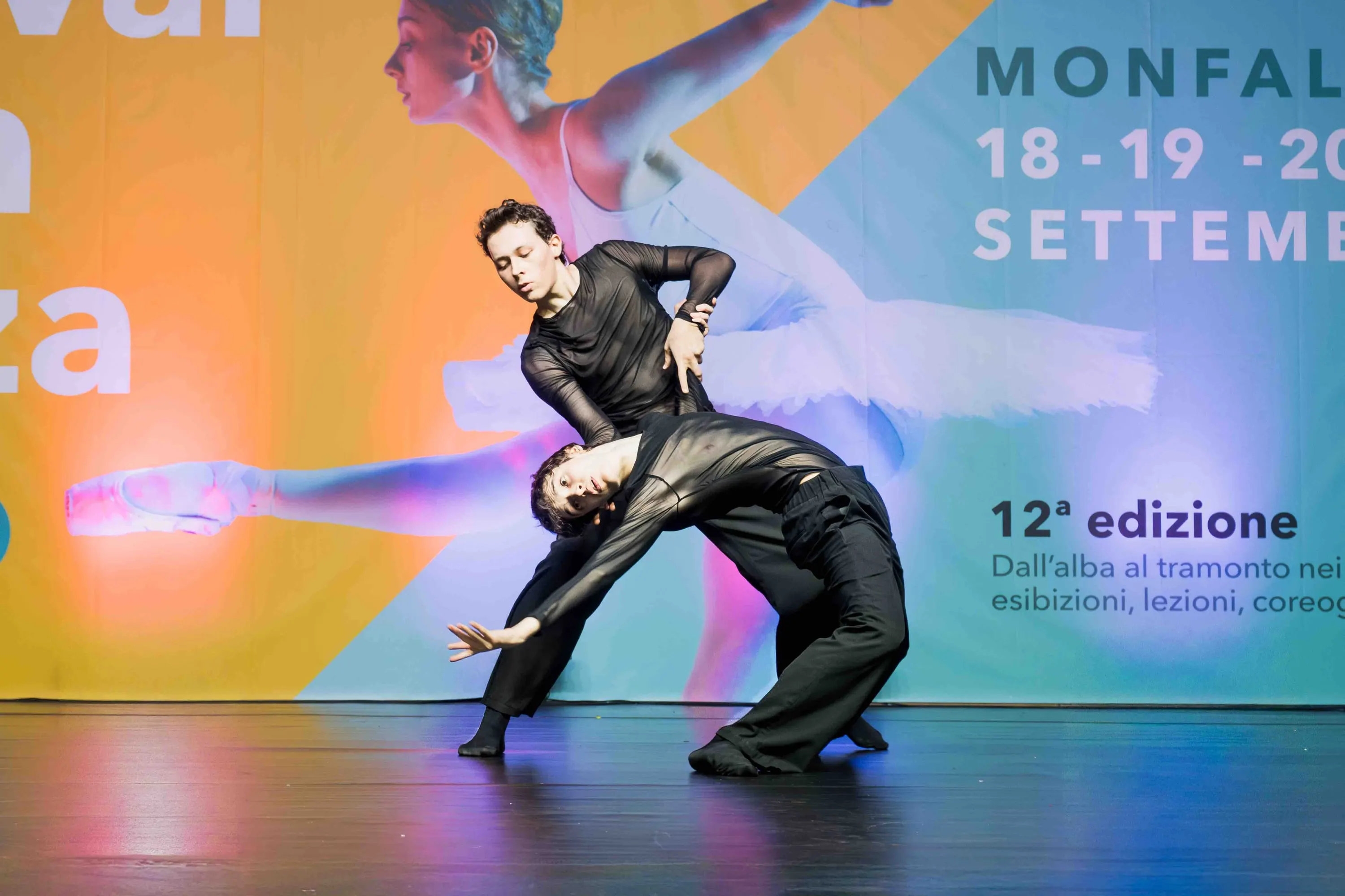 Two dancers in black in a low partnering hold