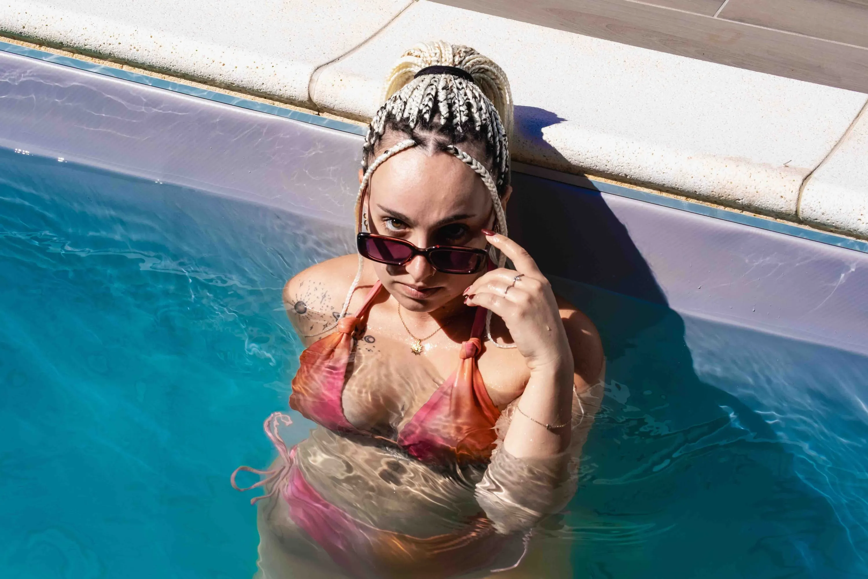 The young woman in the water lowers her sunglasses