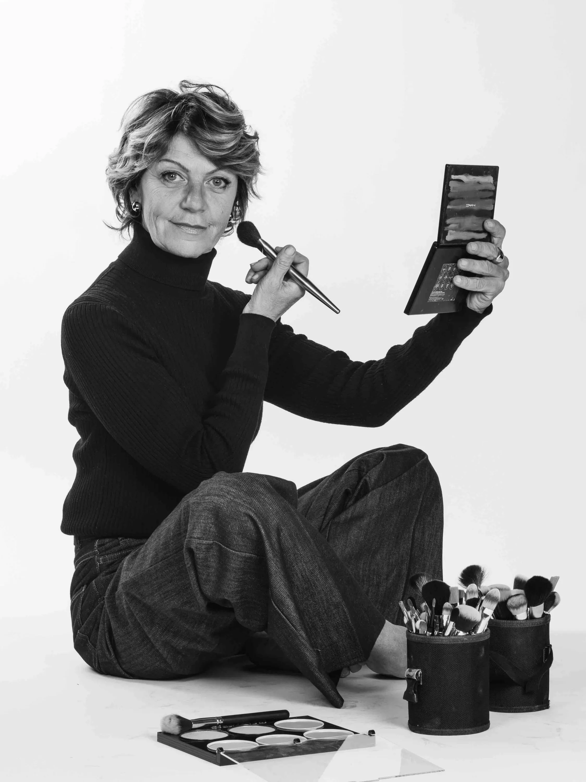 The make-up artist seated holding a brush and a palette