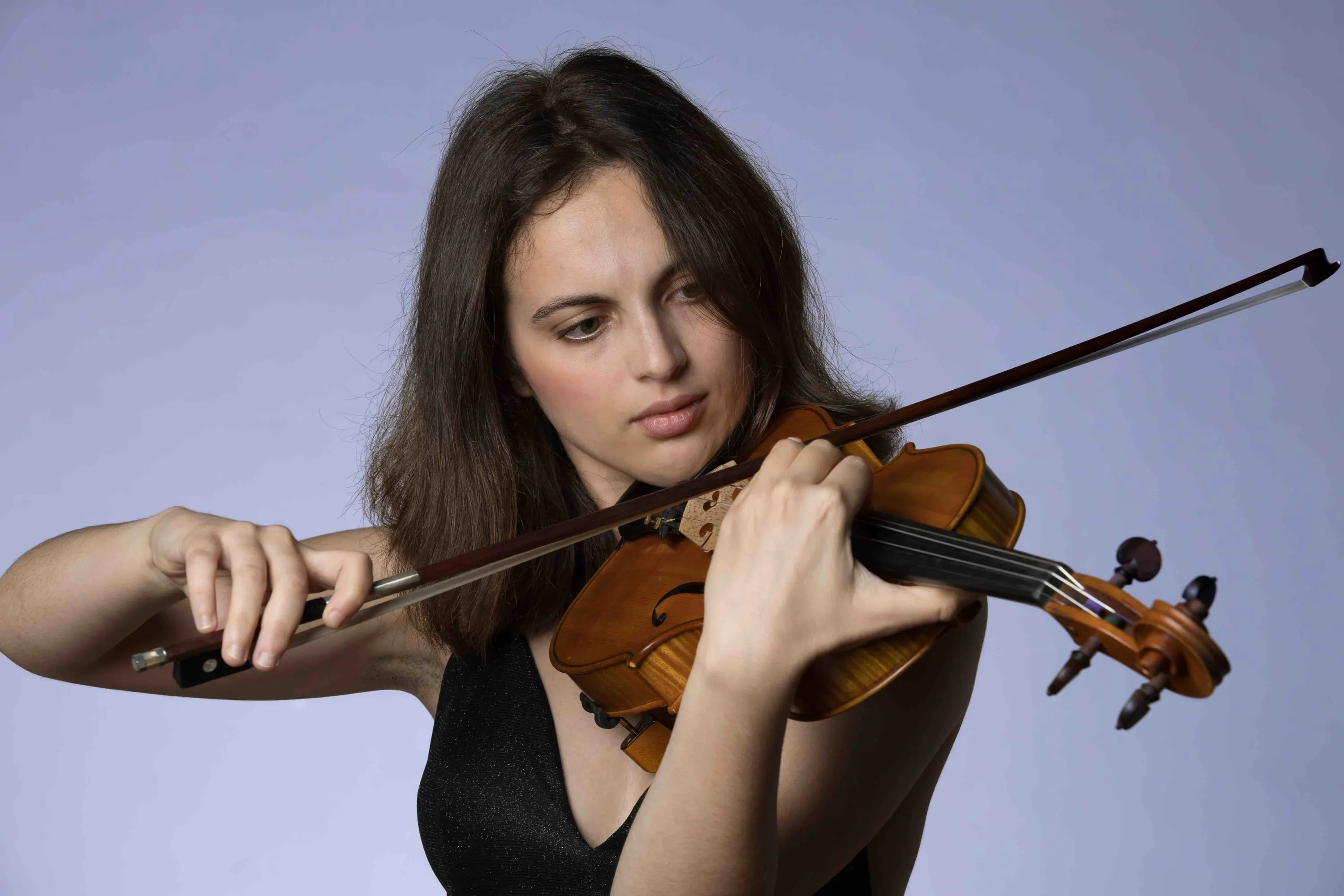 Portrait of a young violinist against a lilac background