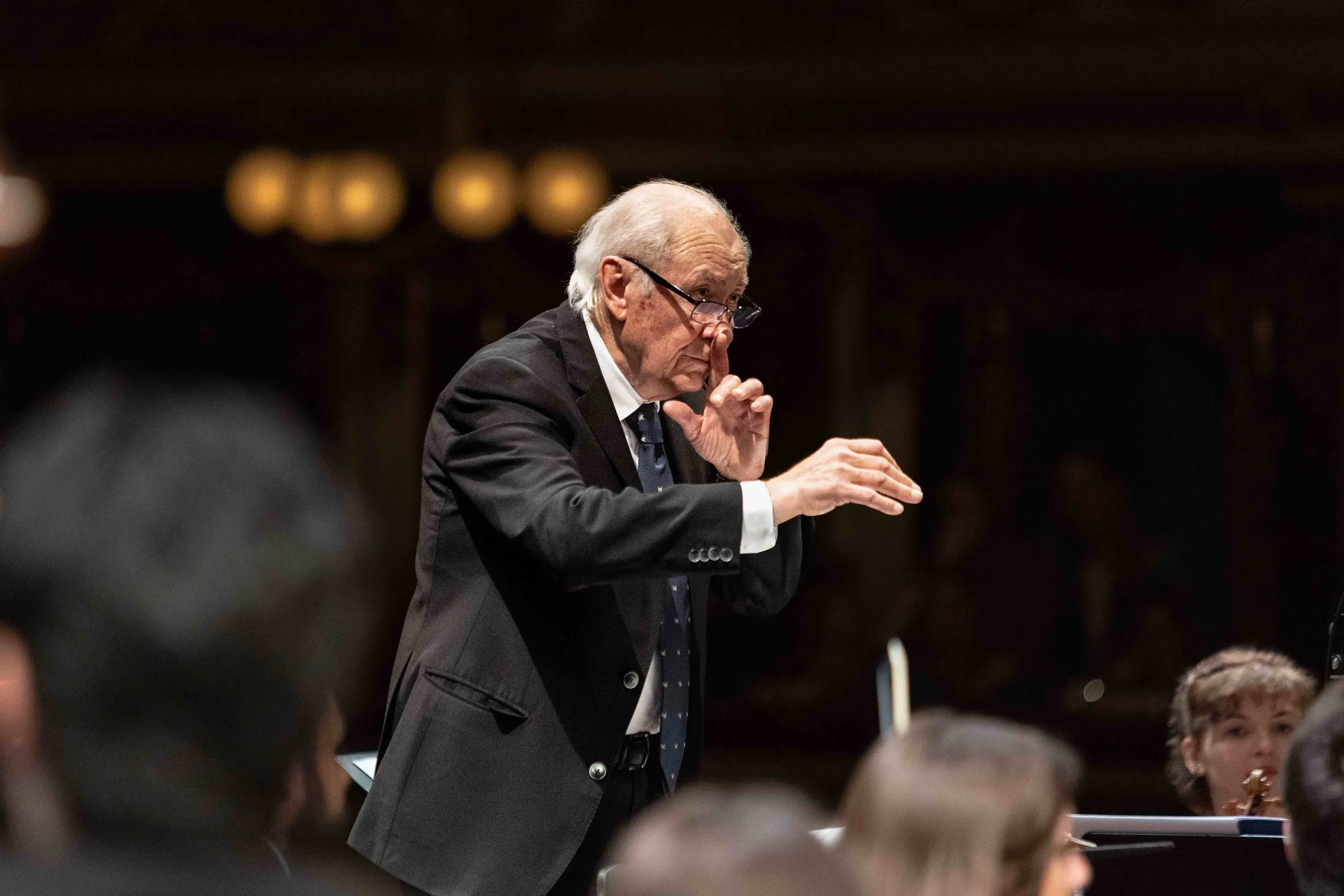 An elderly conductor leads with his hands
