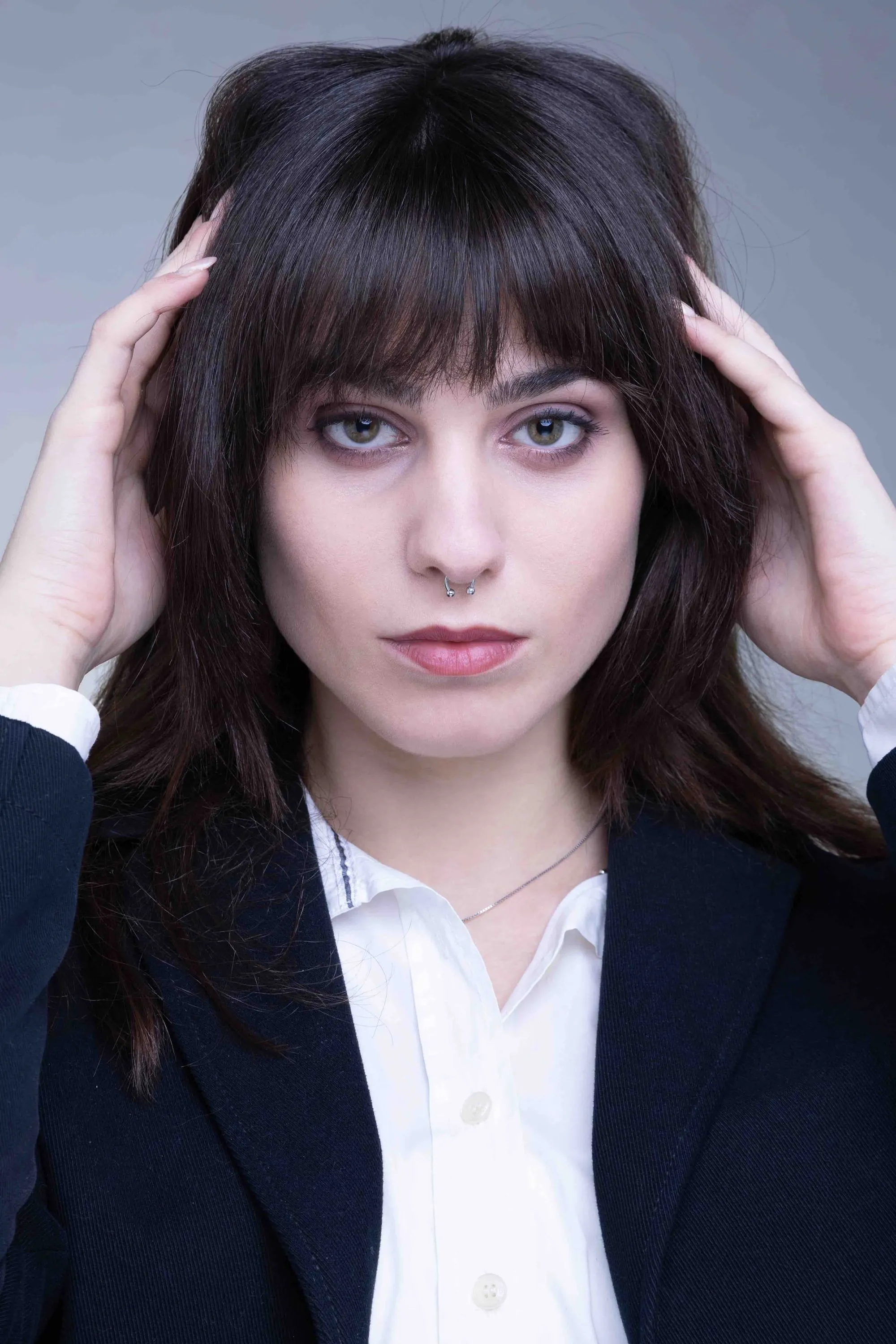 Portrait of a young woman with a fringe and hands in her hair