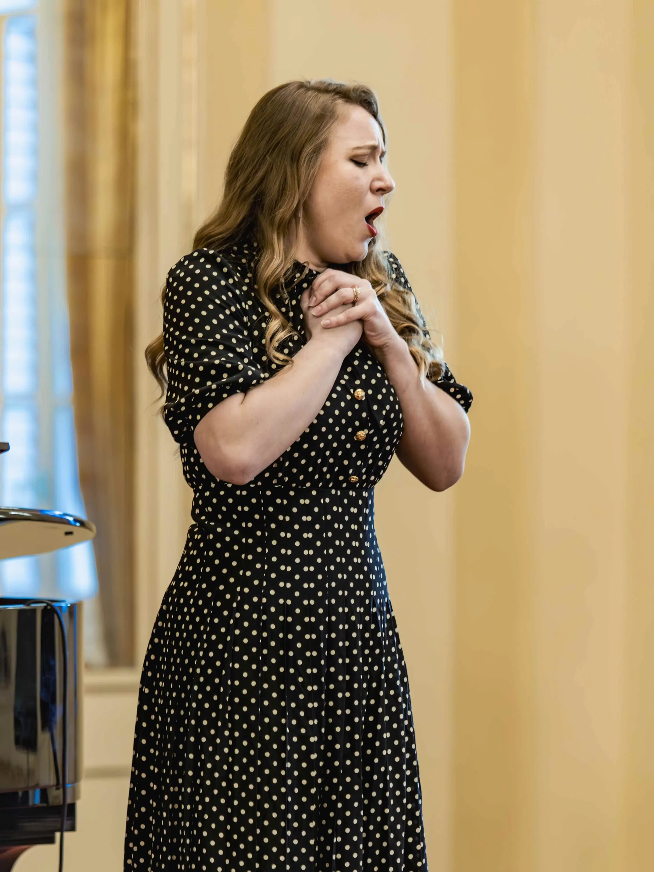 A soprano sings with her hands clasped