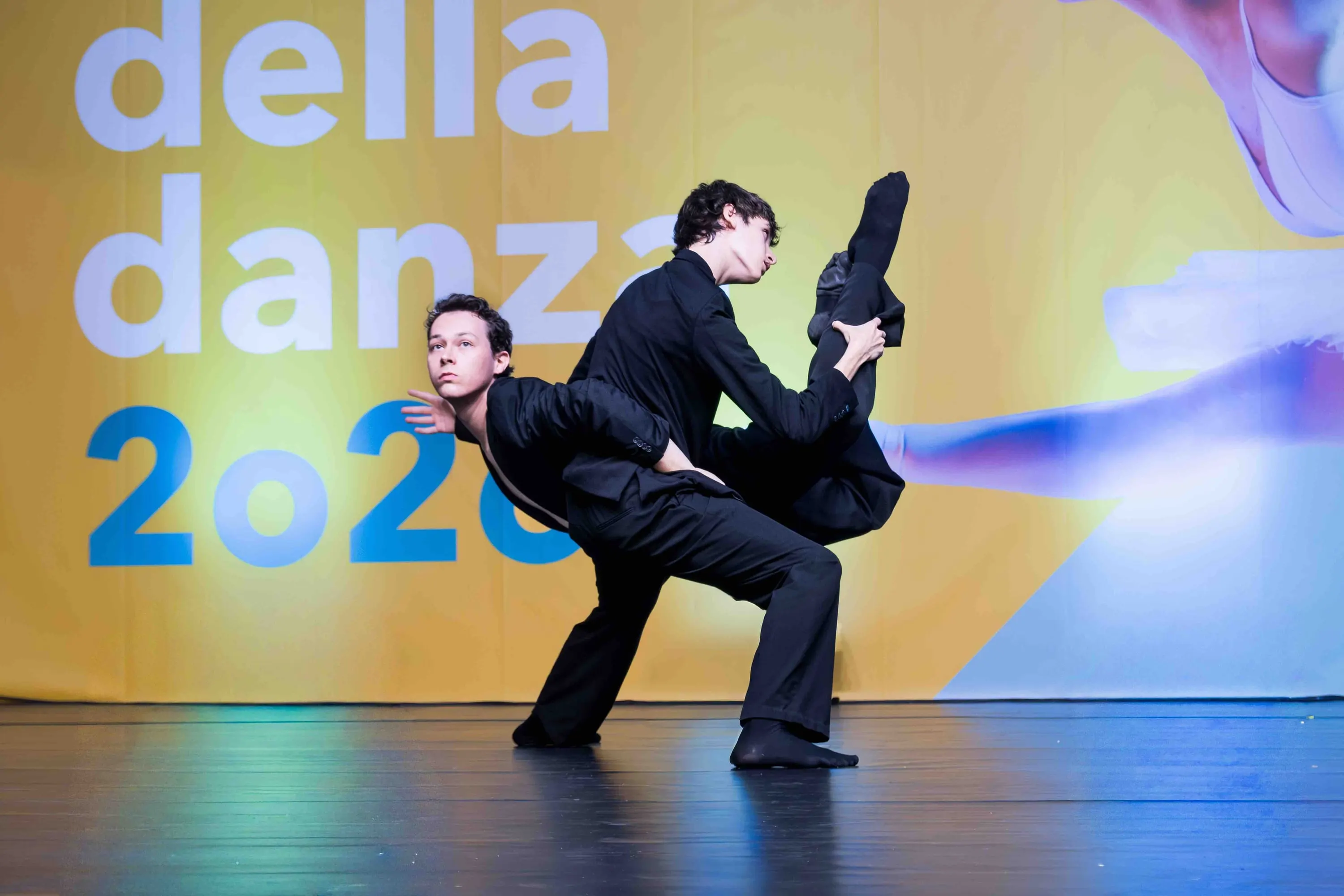 Two dancers in black, one leaning back against the other